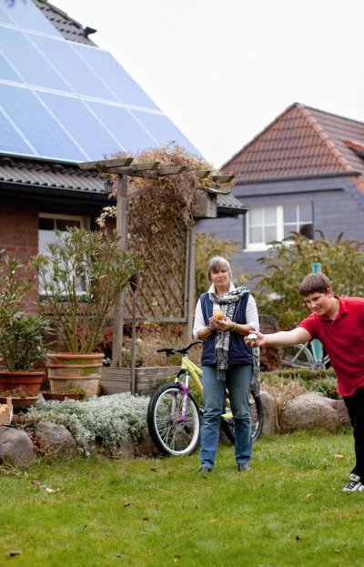 Frau mit Kind vor Photovoltaik Referenzanlage (Bildquelle: REC)